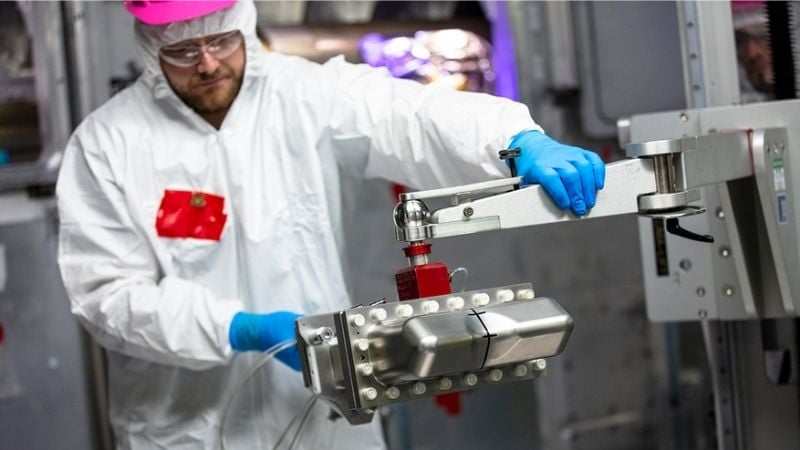 A scientist adjusts the equipment that safely contains material samples for fusion ignition irradiation environments