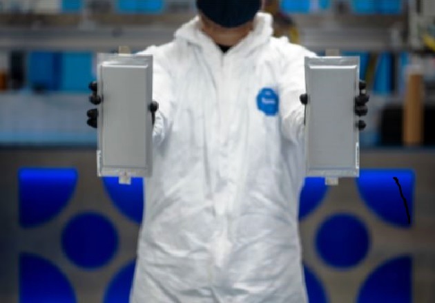  A Solid Power manufacturing engineer holds two 20-ampere hour (Ah) all-solid-state battery cells produced on its Colorado-based pilot production line. Image used courtesy of Solid Power 