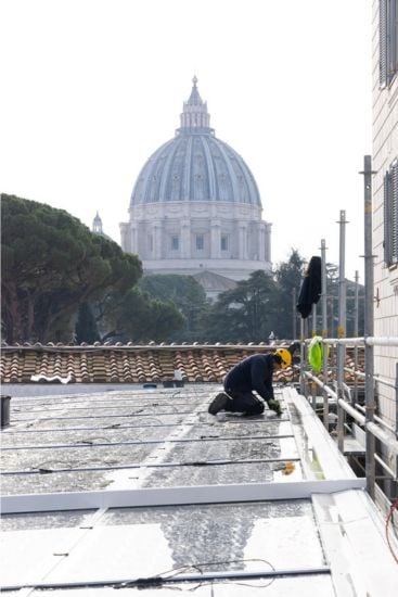 Installation of solar infrastructure atop the Paul VI building. St. Peter’s Basilica (completed in 1626) appears in the background